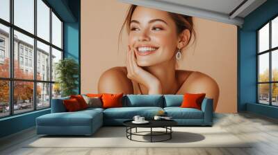 Happy woman wearing earrings and a bracelet, smiling with a cheerful expression, representing joy and elegance in a studio setting. Wall mural