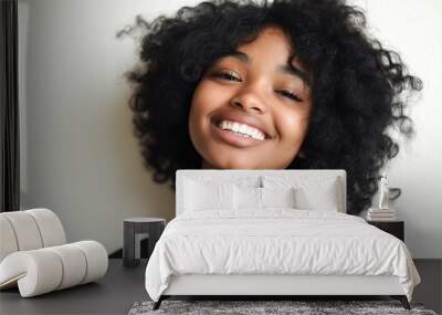 Happy young girl with curly hair, smiling brightly, isolated against a white background, showcasing joy and positivity, with space for text or design. Wall mural