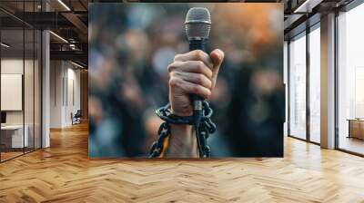 Journalism Freedom: Hand holding a microphone with chain over a blurred crowd in the background, symbol of censorship of freedom of the press and freedom of expression. Copy space Wall mural