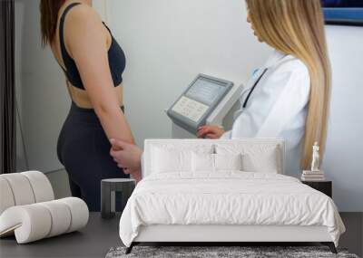 A woman undergoes a body composition analysis with a professional health expert Wall mural