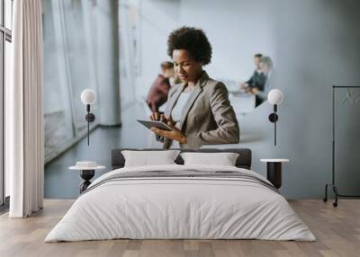 African American businesswoman standing and using digital tablet in a modern office Wall mural