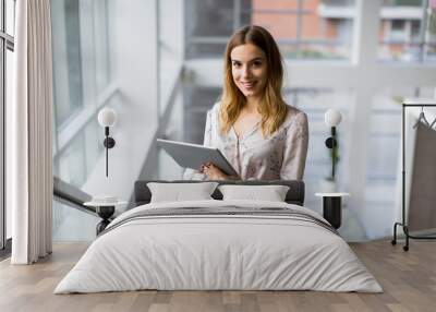 Attractive businesswoman using a digital tablet while standing on the stairs in the office Wall mural