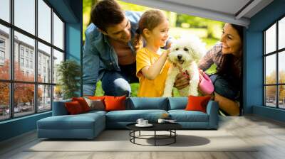 Beautiful happy family is having fun with bichon dog outdoors Wall mural