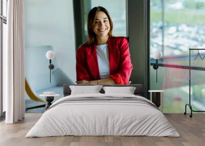 Confident young professional in red blazer smiling at modern office environment Wall mural