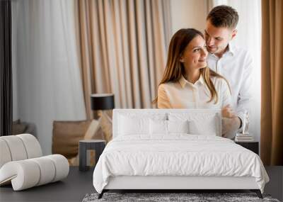 Couple embracing standing in living room of a contemporary apartment Wall mural