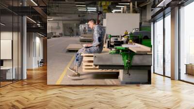 Disabled young man with an artificial leg is working at the furniture  factory Wall mural