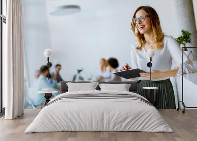 Elegant businesswoman standing in office with digital tablet Wall mural