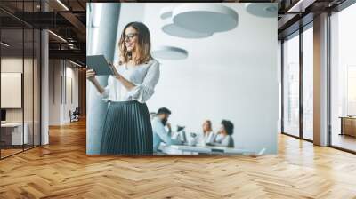 Elegant businesswoman standing in office with digital tablet Wall mural