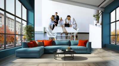 Group of business people with young adults and senior woman colleague on meeting at modern bright office interior Wall mural