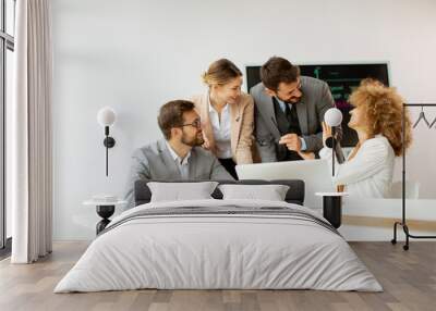 Group of young business people working and communicating while sitting at the office desk together Wall mural