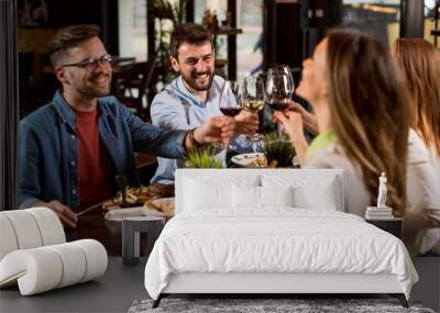 Group of young people having dinner in the restaurant Wall mural