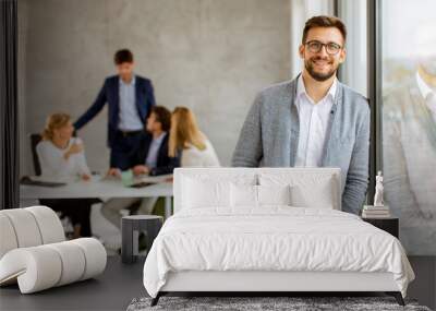 Handsome young business man standing confident in the office Wall mural