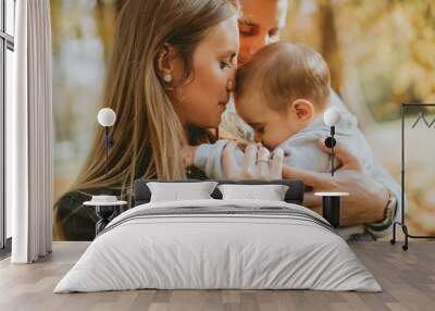 Happy young parents with baby boy in autumn park Wall mural