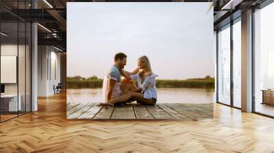 Loving couple sitting on the pier on lake Wall mural