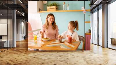 Mother and daughter having a breakfast with fresh squeezed juices in the cafe Wall mural