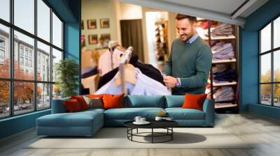 Portrait of a young man looking at clothes to buy at shop Wall mural