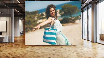 Pretty young woman with a bag on the beach Wall mural