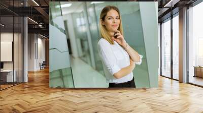 Relaxed confident young businesswoman standing standing in the modern office Wall mural