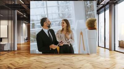 Senior business man and his young female colleague standing in office with digital tablet Wall mural