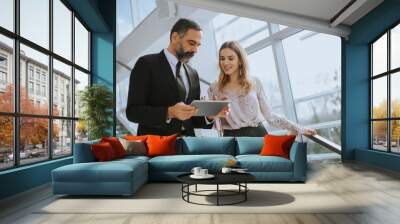 Senior business man and his young female colleague standing in office with digital tablet Wall mural