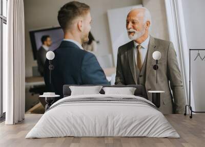 Senior business man handshaking with his young colleague Wall mural