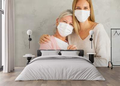 Senior woman with caring daughter at home wearing medical masks Wall mural