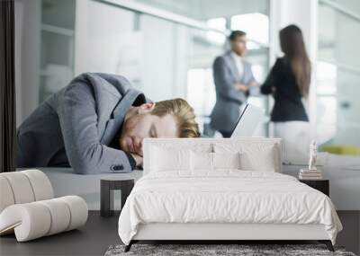 Tired young man sleeping in the office Wall mural