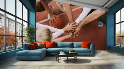 Top view of basketball team holding hands over court Wall mural