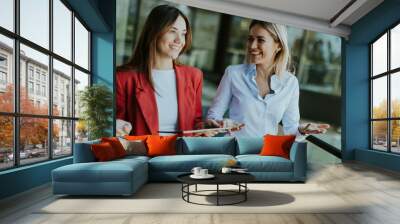 Two businesswomen discuss strategy outside modern office building in daylight Wall mural