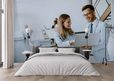 Young business couple working and discussing by laptop in the office Wall mural