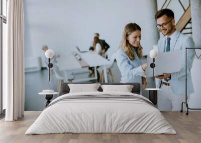 Young business couple working and discussing by laptop in the office Wall mural