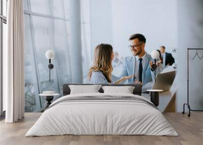 Young business couple working and discussing by laptop in the office Wall mural