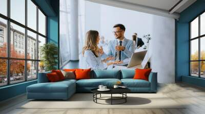 Young business couple working and discussing by laptop in the office Wall mural