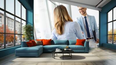 Young business partners making handshake in an office Wall mural