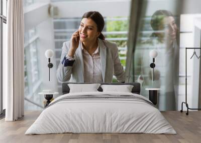 Young business woman stands on the stairs at the office and use mobile phone Wall mural