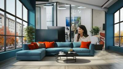 Young business woman working on laptop in the modern office Wall mural