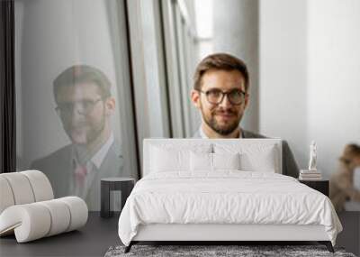 Young businessman standing with digital tablet by the office window Wall mural