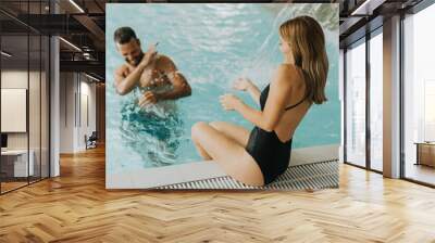 Young couple having fun in the indoor swimming pool Wall mural