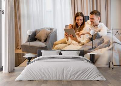 Young couple relaxing at luxurious home with digital tablet Wall mural