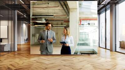 Young coworkers walking and talking along corridor in modern office Wall mural