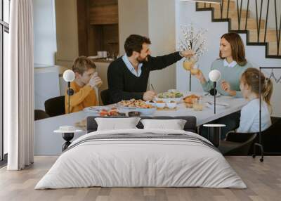 Young happy family talking while having breakfast at dining table Wall mural