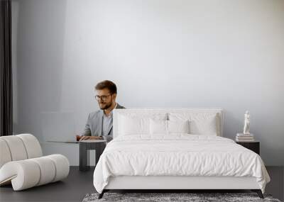 Young man working on laptop in bright office Wall mural