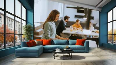 Young mother preparing breakfast for her family in the kitchen Wall mural