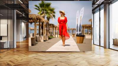 Young woman in red dress walking on a beach at summer Wall mural