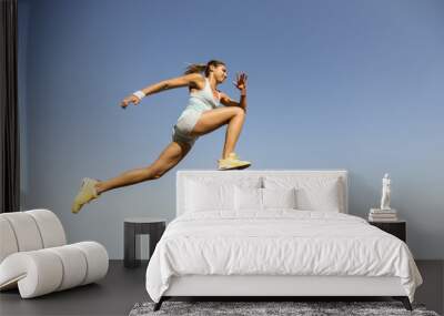 Young woman taking long jump Wall mural