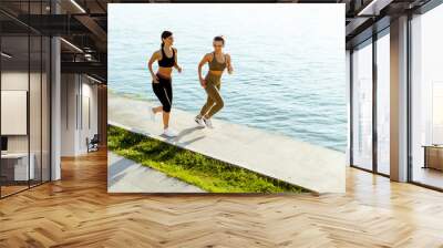 Young woman taking running exercise by the river promenade Wall mural