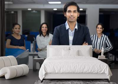 Confident Indian businessman standing infront of his office colleagues, selective focus, corporate environment, team members, business office. Wall mural