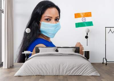 Pretty Indian female wearing Covid-19 protection mask. Cute woman holding Indian national flag. Wall mural