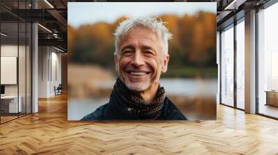 Blond hair caucasian man in his 50s who exudes happiness and a sense of feeling truly alive in a beautiful natural park near lake, genuine smile on his face, relaxed and confident male who found joy Wall mural