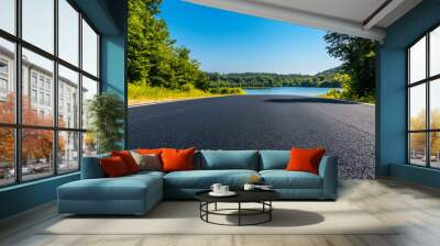 Empty asphalt road and green trees with blue sky background over the lake in summer landscape nature view from side of empty street for product display Wall mural